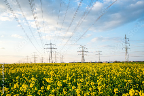 A lot of high-voltage power line, electrical energy transmission tower overhead line masts, high voltage pylons as power pylons on the fields