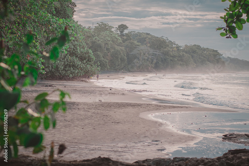 Beautiful jungle caribbean beach with nice surf close to Playa Cocles and Puerto Viejo in Costa rica. View through bushes. -hazy sea and spray. photo