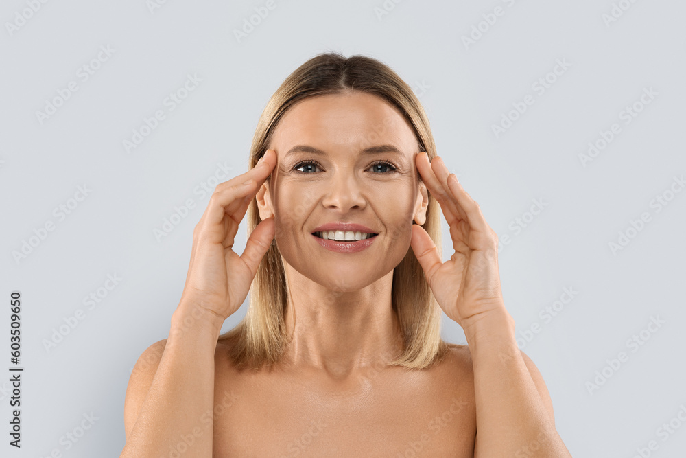 Closeup of pretty middle aged blonde woman touching eyes area Closeup of pretty middle aged blonde woman touching eyes area