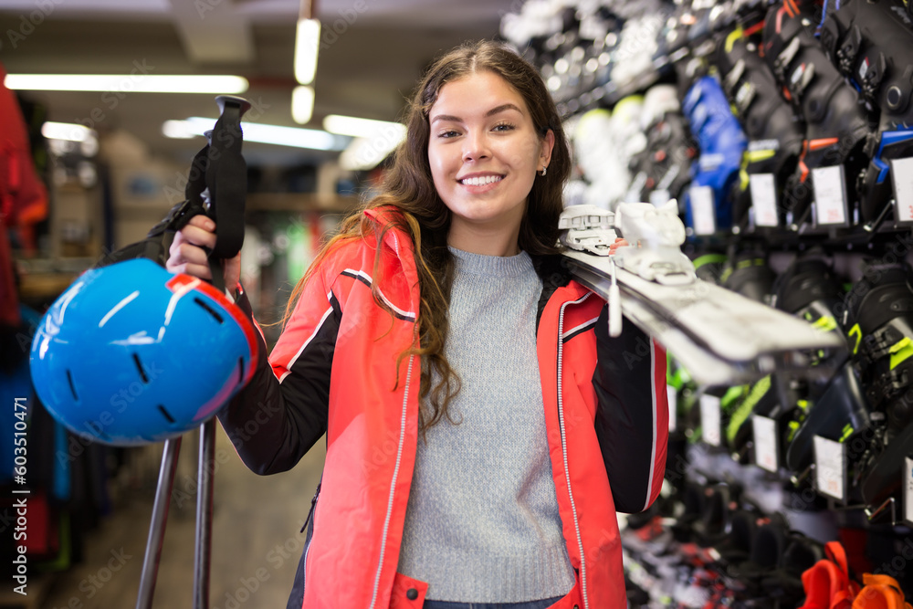 Portrait of girl in skiing outfit satisfied with choice in modern store of sports equipment