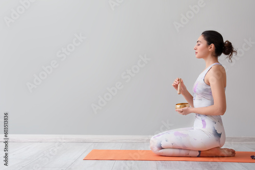 Foto Beautiful young woman with Tibetan singing bowl at home