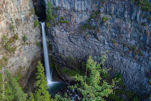 Waterfall with its full leap from the mountain to the Murtle River. Waterfall plunging into the green waters of the river. Helmcken Falls is a 141 m (463 ft) waterfall on the Murtle River within Wells photo