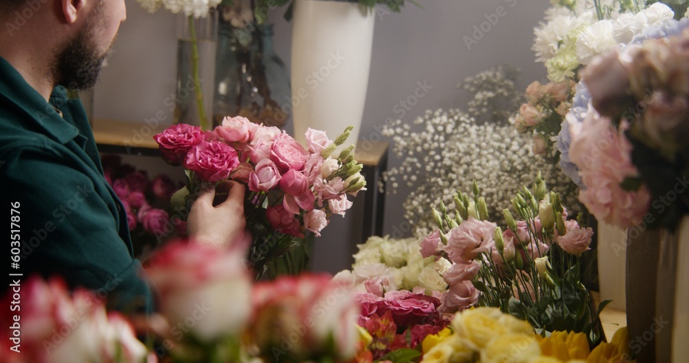 Male professional florist, entrepreneur, seller takes fresh flowers from vase and collects bouquet for client in flower store. Concept of floristry, floral retail small business and entrepreneurship. Male professional florist, entrepreneur, seller takes fresh flowers from vase and collects bouquet for client in flower store. Concept of floristry, floral retail small business and entrepreneurship.