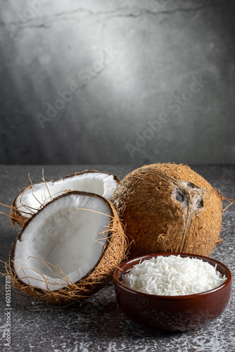 Whole coconut, pieces of coconut and shredded coconut on the table.