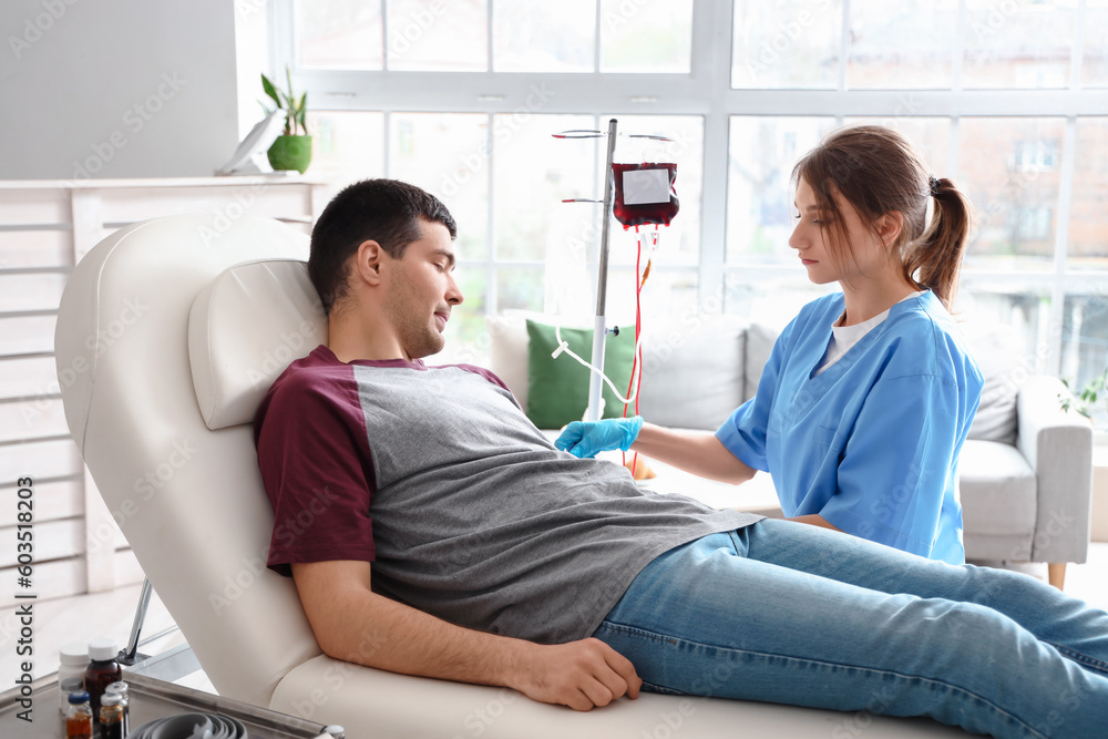 Fototapeta premium Female nurse taking blood from young donor in clinic