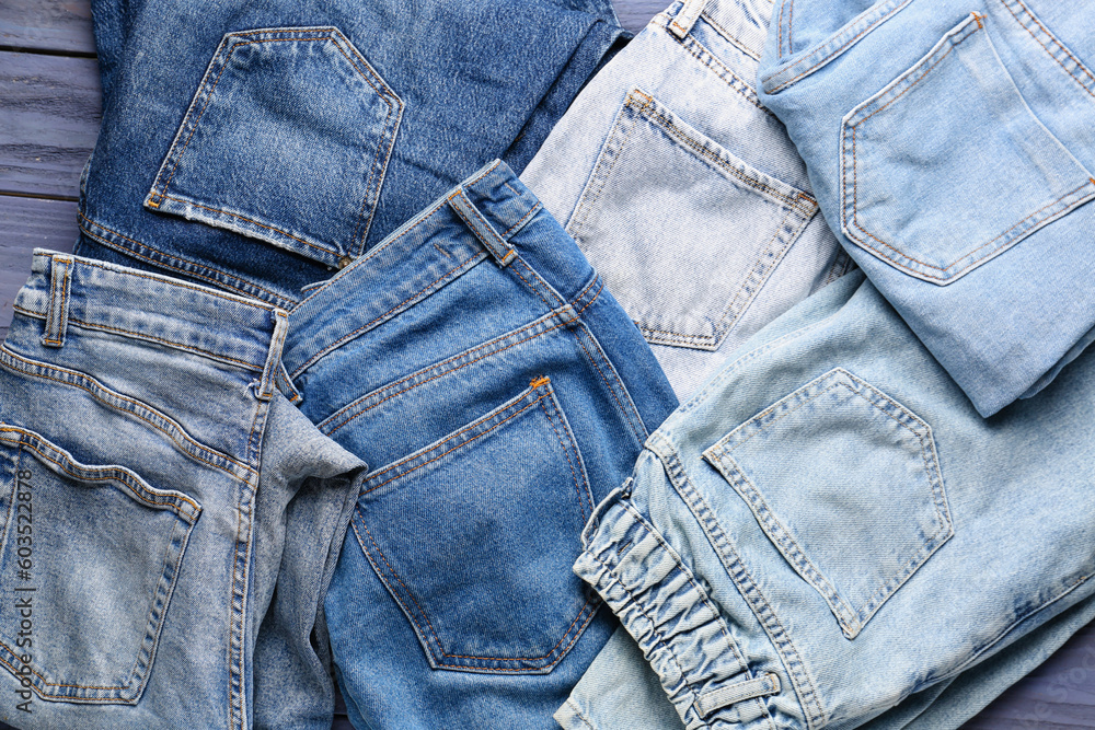 Different stylish denim jeans on blue wooden background Different stylish denim jeans on blue wooden background