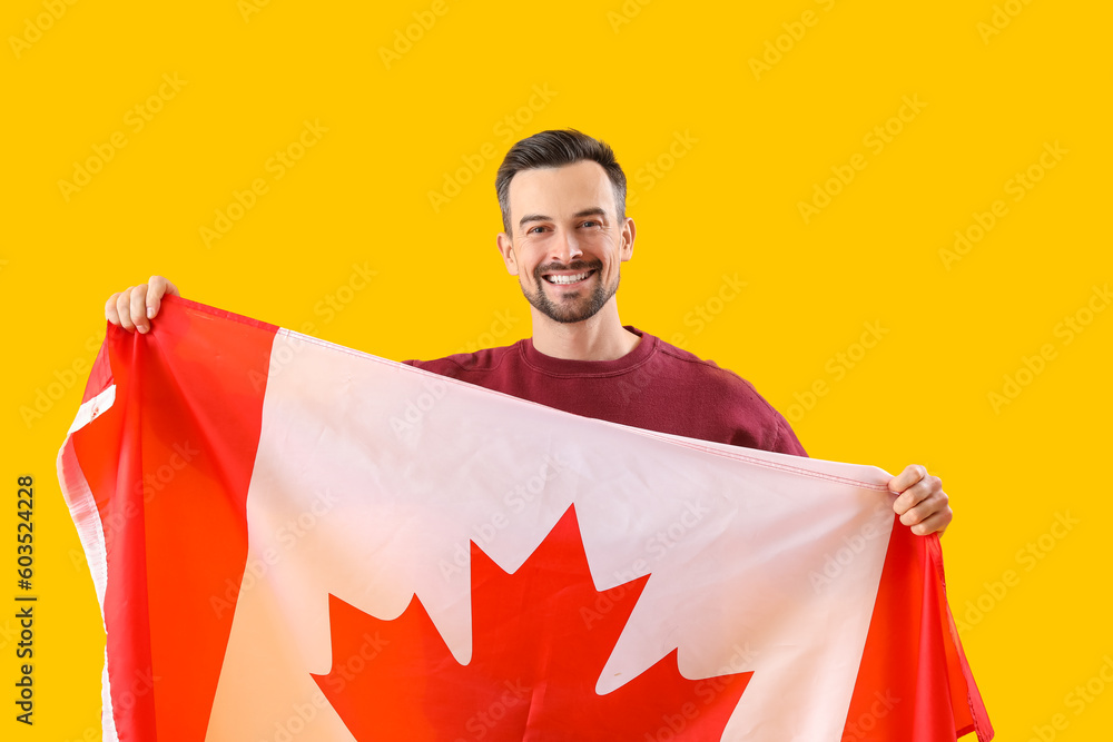 Handsome man with flag of Canada on yellow background - obrazy, fototapety, plakaty 