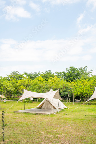 Camping tents on the grassland of the park under the blue sky and white clouds