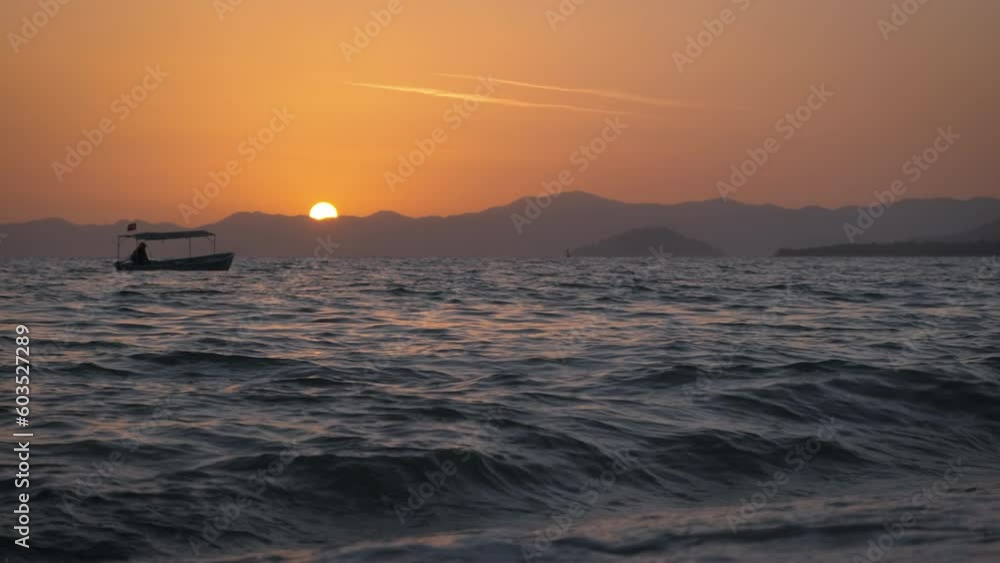 Fishing boat silhouette on empty ocean. A lonely fishing silhouette sailing in the large foaming ocean during orange nightfall in summer. Fishing boat silhouette on empty ocean. A lonely fishing silhouette sailing in the large foaming ocean during orange nightfall in summer.