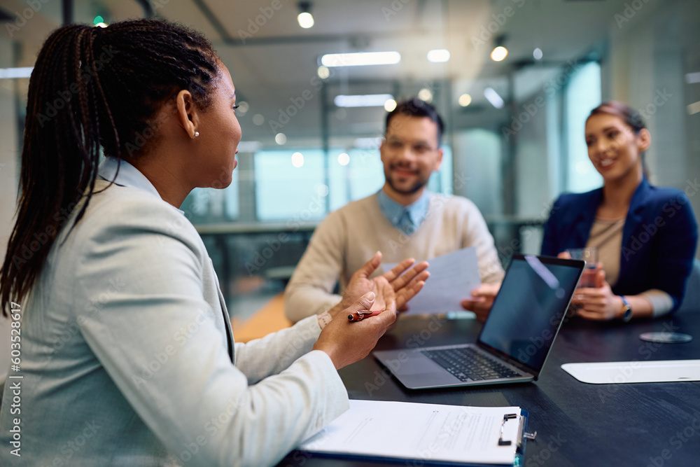 Black female financial advisor talks to couple during meeting in office. Black female financial advisor talks to couple during meeting in office.