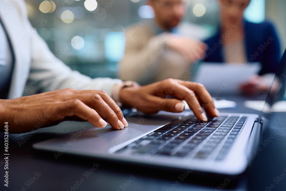Close up of black financial advisor working on laptop during meeting with her clients. Close up of black financial advisor working on laptop during meeting with her clients.