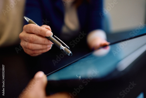 Close up of woman signing an agreement on touchpad during meeting with insurance agent.
