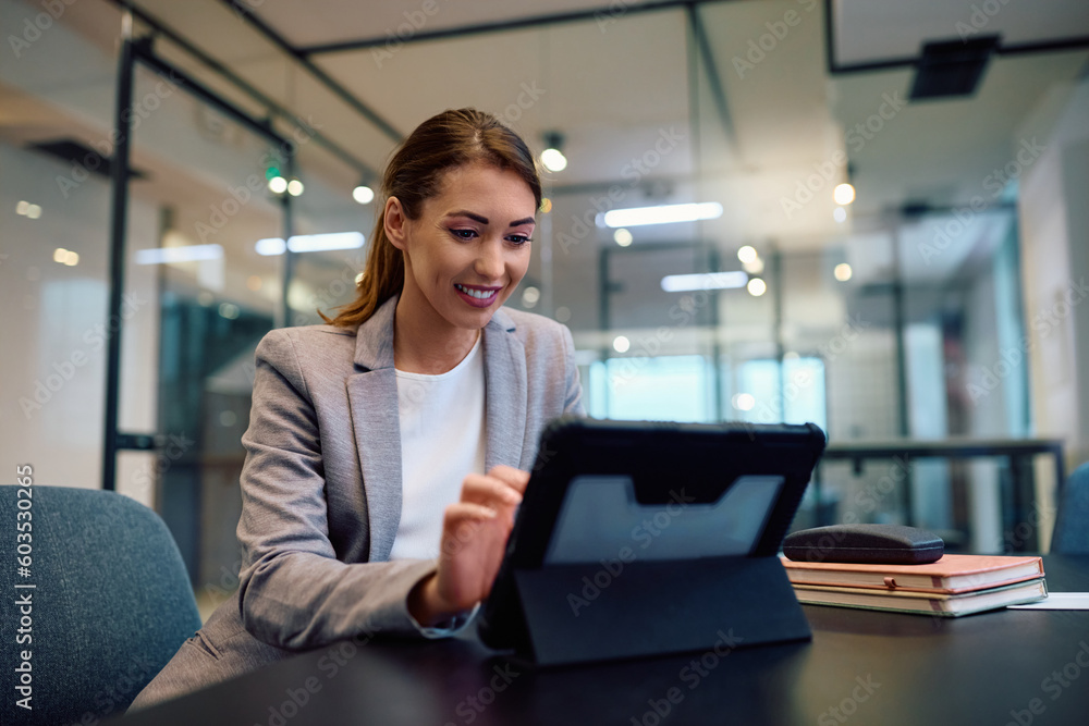 Young happy businesswoman working on digital tablet in office. Young happy businesswoman working on digital tablet in office.