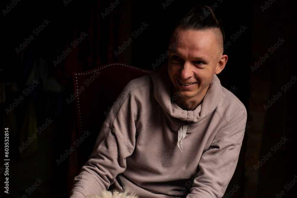 Carefree middle aged man in smiling. Relaxed posture, casual wear. Dark background. Carefree middle aged man in smiling. Relaxed posture, casual wear. Dark background.