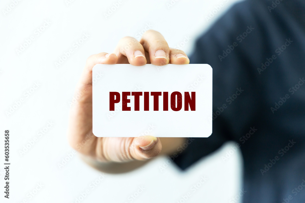 Petition text on blank business card being held by a woman's hand with blurred background. Business concept about petition. Petition text on blank business card being held by a woman's hand with blurred background. Business concept about petition.