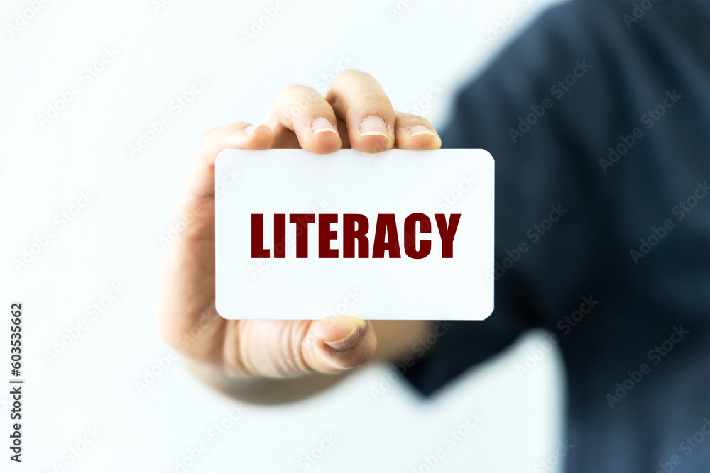 Literacy text on blank business card being held by a woman's hand with blurred background. Business concept about literacy. Literacy text on blank business card being held by a woman's hand with blurred background. Business concept about literacy.