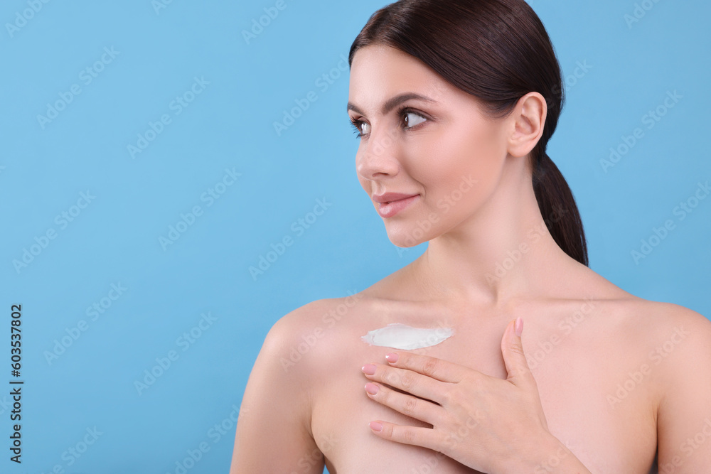 Beautiful woman with smear of body cream on her collarbone against light blue background, space for text Beautiful woman with smear of body cream on her collarbone against light blue background, space for text