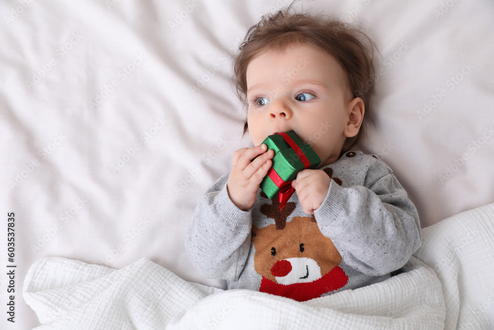Cute little baby with gift on soft bed, top view. Space for text Cute little baby with gift on soft bed, top view. Space for text