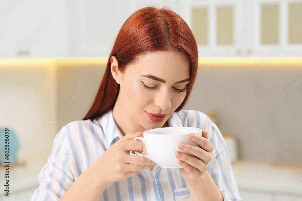 Beautiful woman with red dyed hair enjoying cup of drink in kitchen Beautiful woman with red dyed hair enjoying cup of drink in kitchen