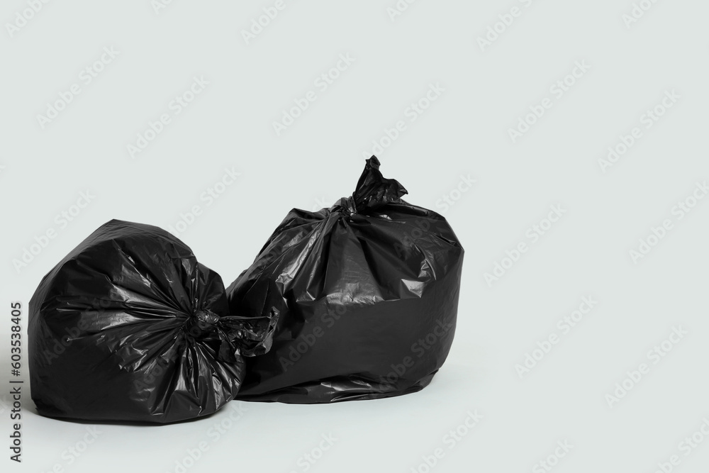 Trash bags full of garbage on light grey background. Space for text