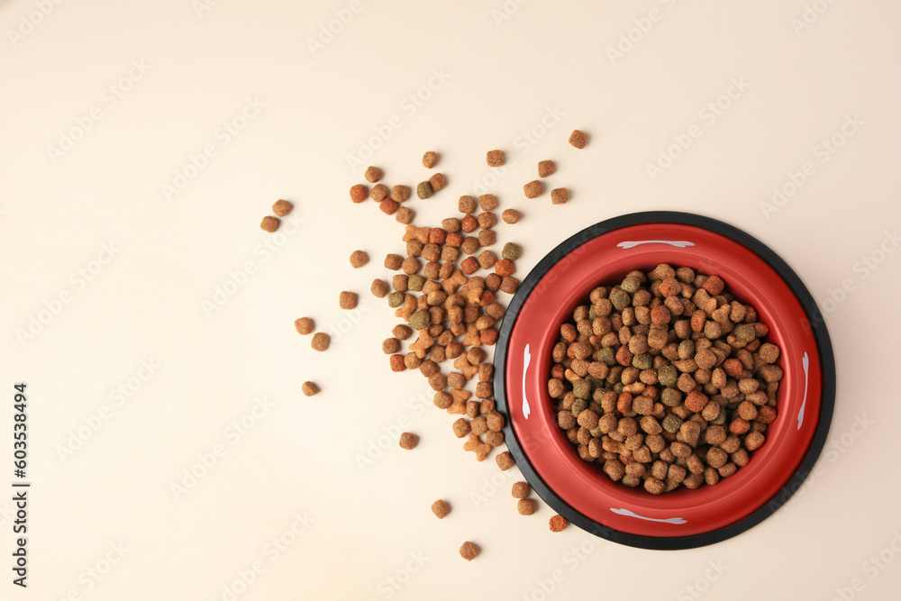 Dry dog food and feeding bowl on beige background, flat lay. Space for text Dry dog food and feeding bowl on beige background, flat lay. Space for text