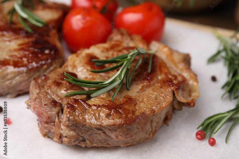 Delicious fried meat with rosemary, tomatoes and spices on white table, closeup Delicious fried meat with rosemary, tomatoes and spices on white table, closeup