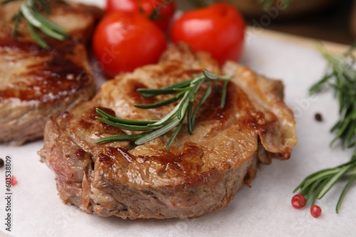 Delicious fried meat with rosemary  tomatoes and spices on white table  closeup