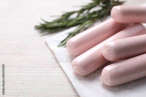 Vegan sausages and rosemary on white wooden table, closeup. Space for text