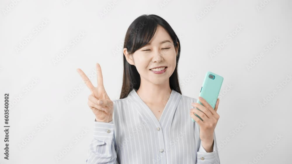 スマートフォンを持ちながらグッドサインをする若い女性
スマートフォンを持ちながらグッドサインをする若い女性