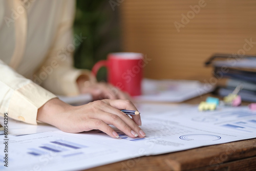 Female accountant employee analyzing data, graphs charts, report at her working desk.