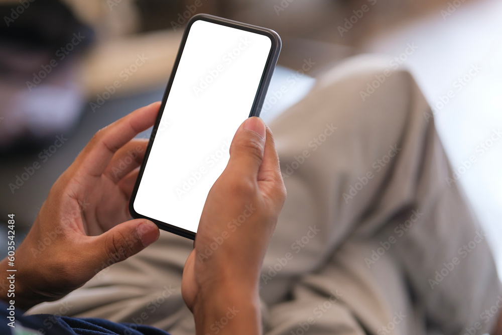 Cropped shot of man holding smartphone with mockup white blank display, empty screen for app ads. Cropped shot of man holding smartphone with mockup white blank display, empty screen for app ads.