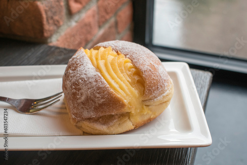 Portuguese doughnut or Berliner with egg creme over a white plate.