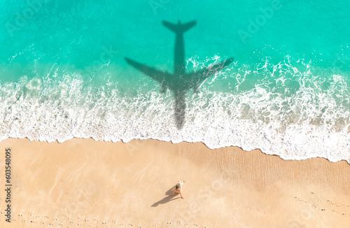 Fototapeta Naklejka Na Ścianę i Meble -  Aerial view of a woman sunbathing at white sand of a tropical beach - Airplane shadow over turquoise water - Summer vacation background.