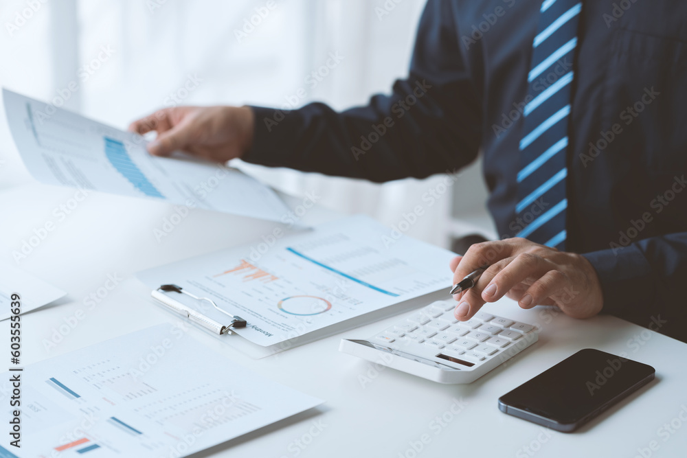 Businessman working in office using calculator to calculate numbers, financial accounting concept for company progress and growth management system concept finance and tax. Businessman working in office using calculator to calculate numbers, financial accounting concept for company progress and growth management system concept finance and tax.