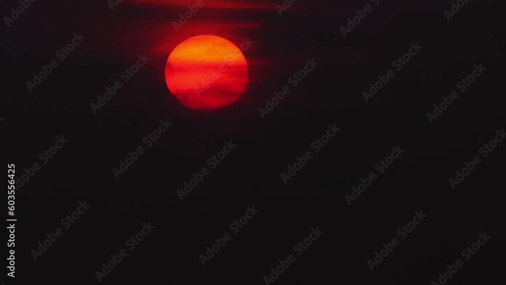 Red sun in a gray dramatic cloudy sky at sunset Red sun in a gray dramatic cloudy sky at sunset