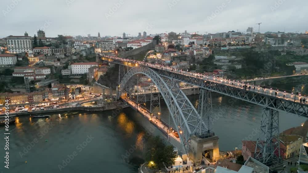 Slow panning shot of a brightly lit Luís I Bridge with people crossing over the river Slow panning shot of a brightly lit Luís I Bridge with people crossing over the river