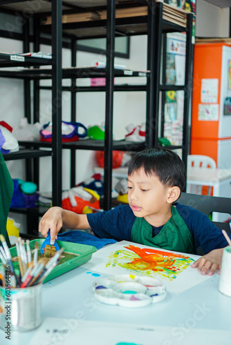 Cute little asian boy kids doing art painting activities in the classroom on the table, Indonesian, Malaysian
