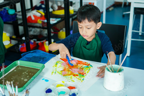 Cute little asian boy kids doing art painting activities in the classroom on the table, Indonesian, Malaysian