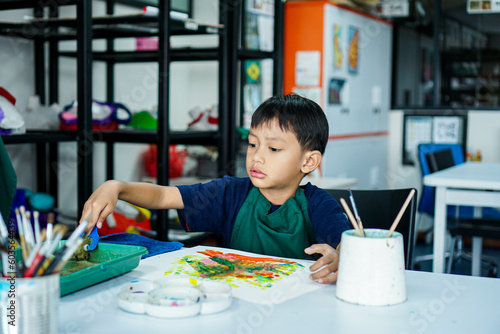 Cute little asian boy kids doing art painting activities in the classroom on the table, Indonesian, Malaysian