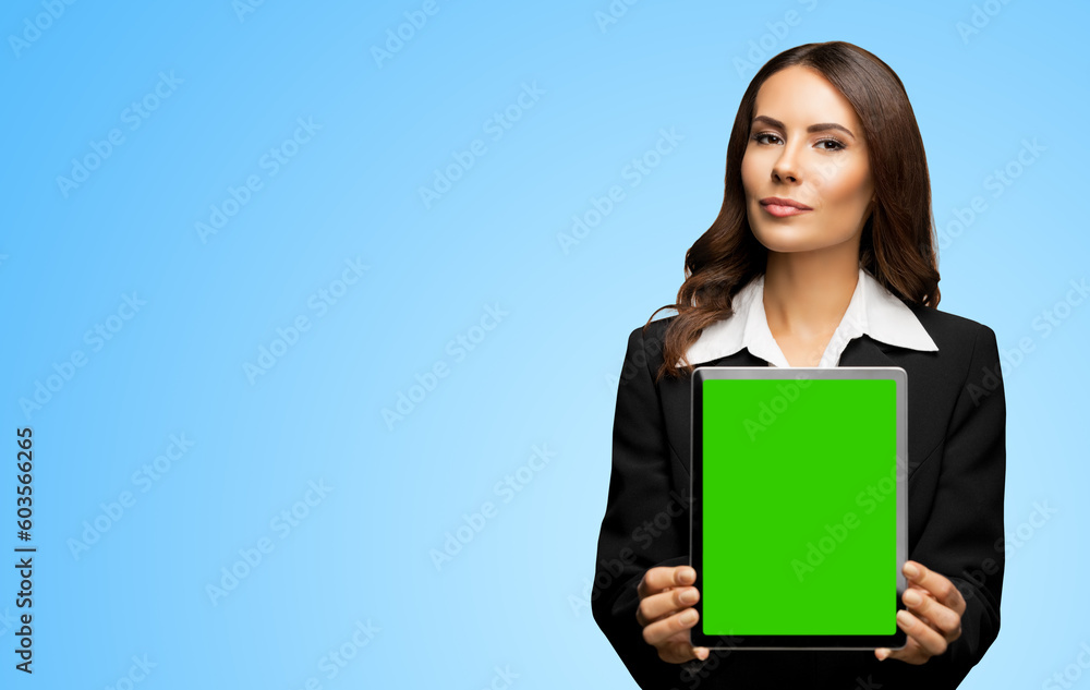Portrait of young brunette businesswoman showing tablet pc, touchpad, with green chroma key screen, on sky blue background. Confident attractive business woman at office. Portrait of young brunette businesswoman showing tablet pc, touchpad, with green chroma key screen, on sky blue background. Confident attractive business woman at office.