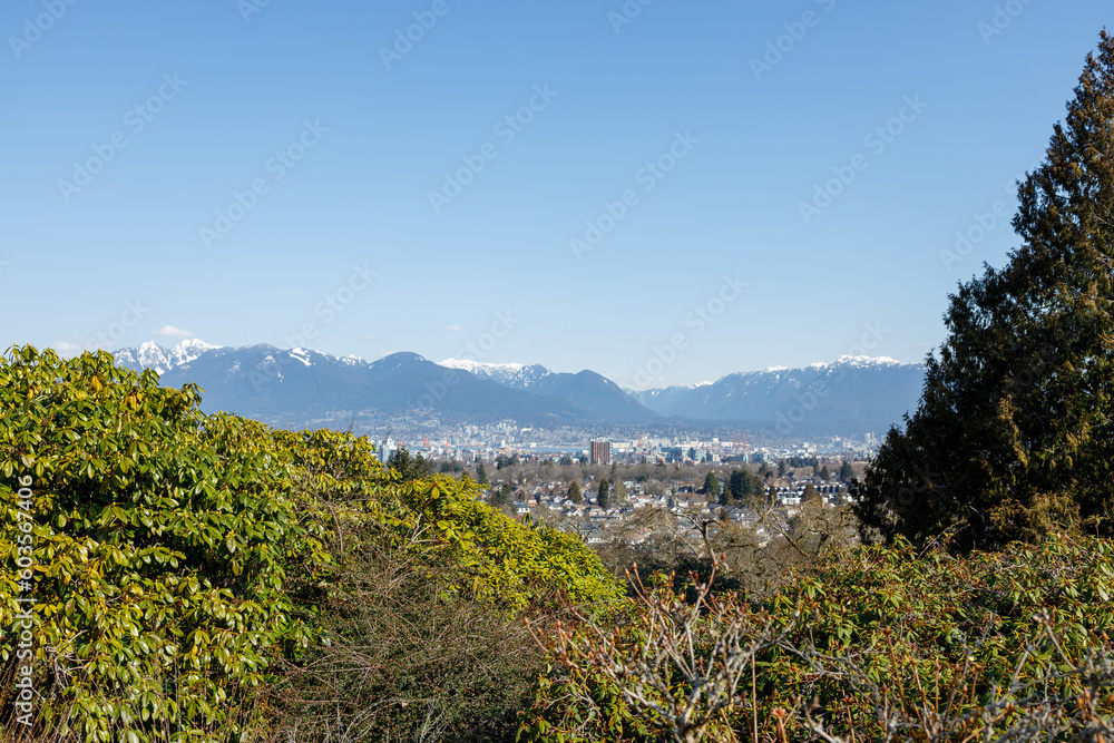 The photo showcases a beautiful viewpoint inside Queen Elizabeth Park in Vancouver, with majestic mountains serving as the stunning backdrop.