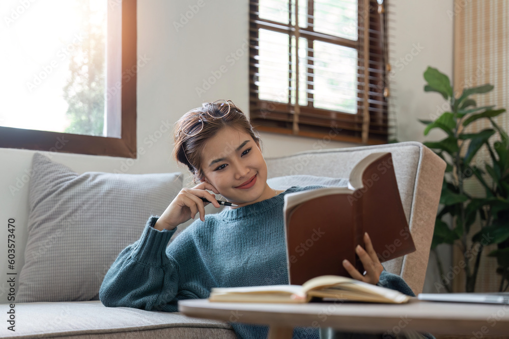 Pretty smiling woman relaxing at home sitting on sofa reading book Pretty smiling woman relaxing at home sitting on sofa reading book