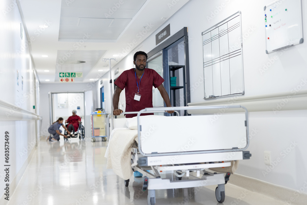 African american male medical worker pushing empty bed in hospital corridor African american male medical worker pushing empty bed in hospital corridor