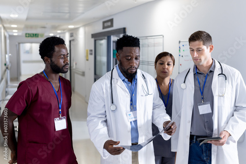 Diverse male and female doctors with stethoscopes inspecting xray on corridor