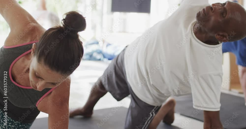 Focused group of unaltered diverse seniors practicing pilates on mats at house in slow motion