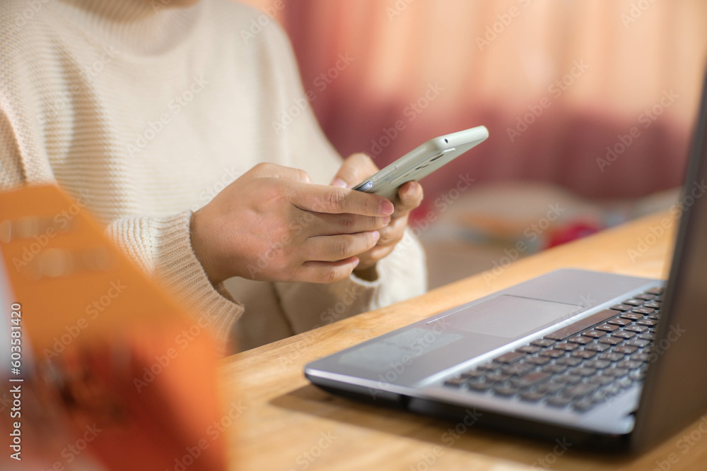 Young Asian woman using smartphone and working sitting in office at home close-up. Young Asian woman using smartphone and working sitting in office at home close-up.