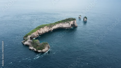 A view from a flying plane height of a lonely beautiful elongated tropical island with rocky shores in the ocean. Flying around the island washed by a strong ocean current. Drone copter footage. photo