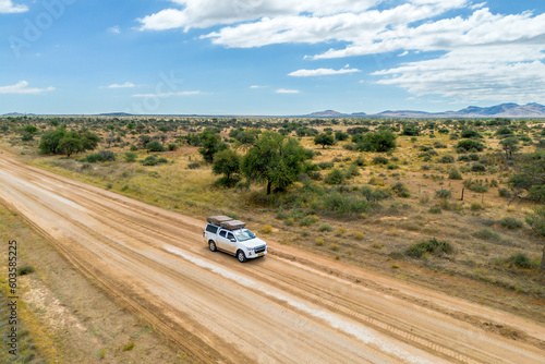 Drone image of offroad vehicle driving on dirt road in African bush