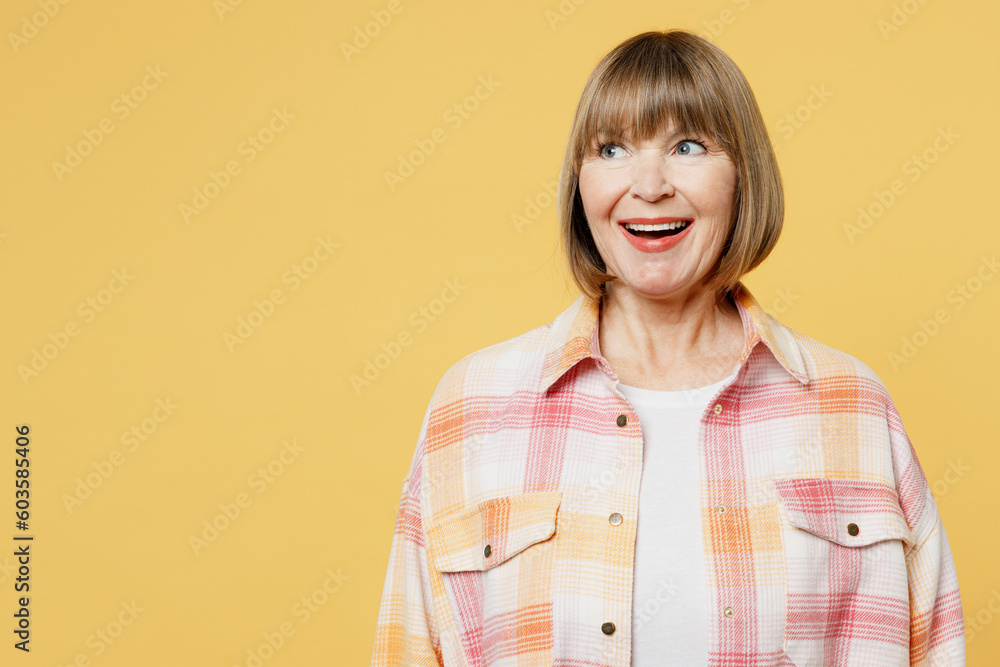 Elderly blonde surprised shocked fun amazed caucasian woman 50s years old she wear casual clothes look aside on workspace area isolated on plain yellow background studio portrait. Lifestyle concept. Elderly blonde surprised shocked fun amazed caucasian woman 50s years old she wear casual clothes look aside on workspace area isolated on plain yellow background studio portrait. Lifestyle concept.