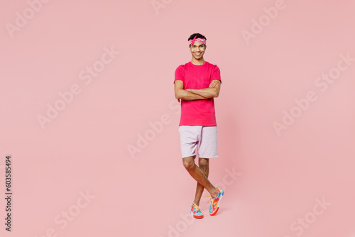 Full body young man of African American ethnicity he wear headscarf t-shirt casual clothes hold hands crossed folded look camera isolated on pastel plain light pink color background studio portrait.